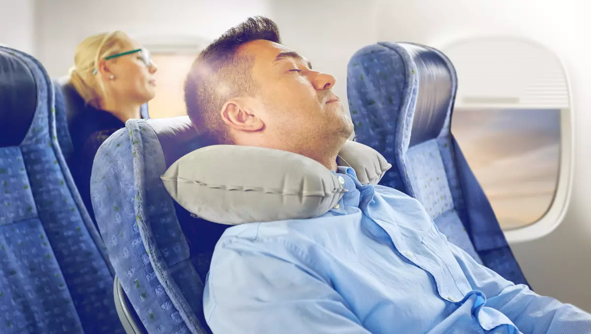 A men sleeping in flight wearing travel Pillow