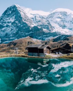 brown wooden house and mountain reflecting on lake