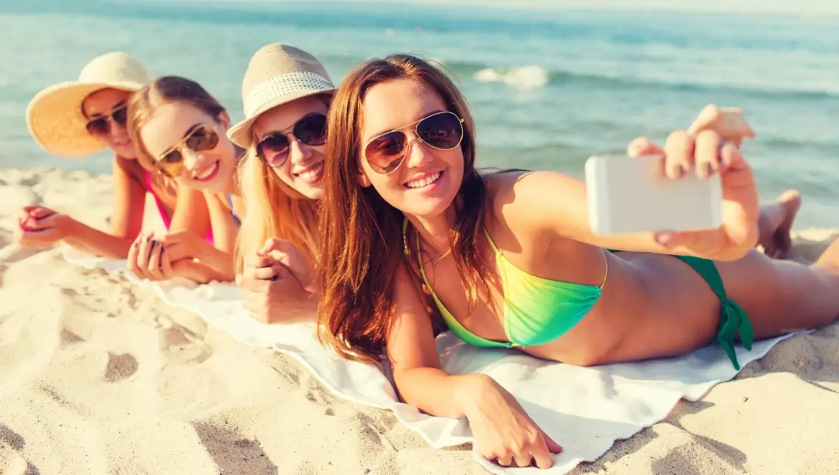 Three girls taking sun bath on beach and taking selfie | Beach Outfits For Women