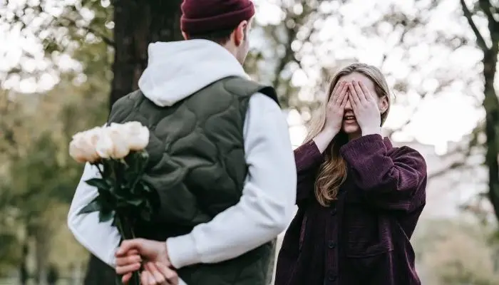 Boy purposing a girl and hiding flowers at back